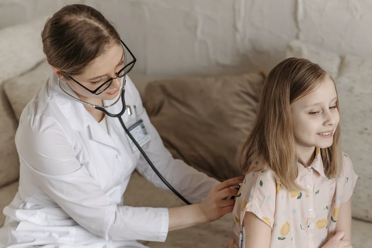 A doctor listening to a girl's chest